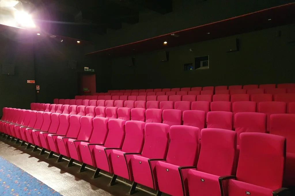 Boş bir sinema salonunda kırmızı koltuk sıraları — festival gösterimi öncesi